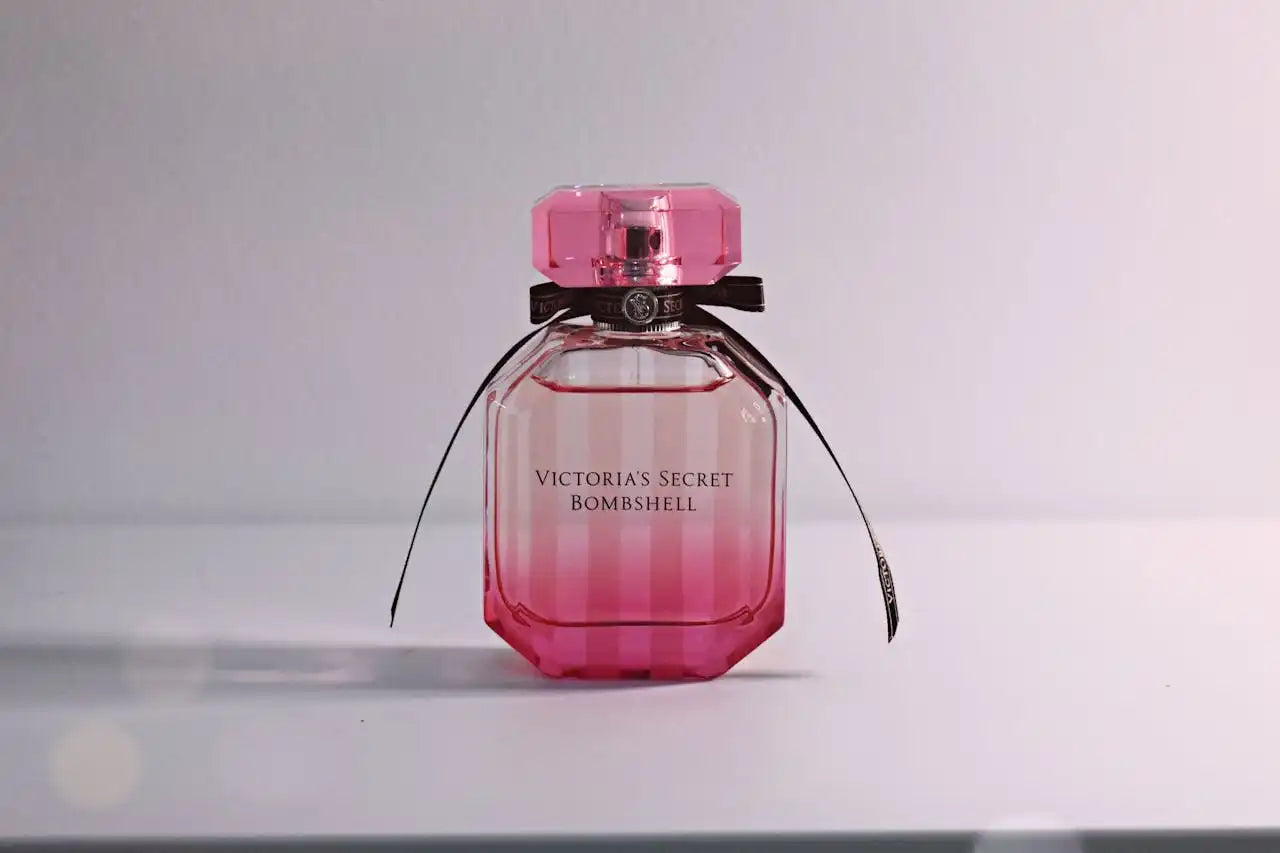 Pink perfume bottle labeled ’Victoria’s Secret Bombshell’ with a black ribbon bow.